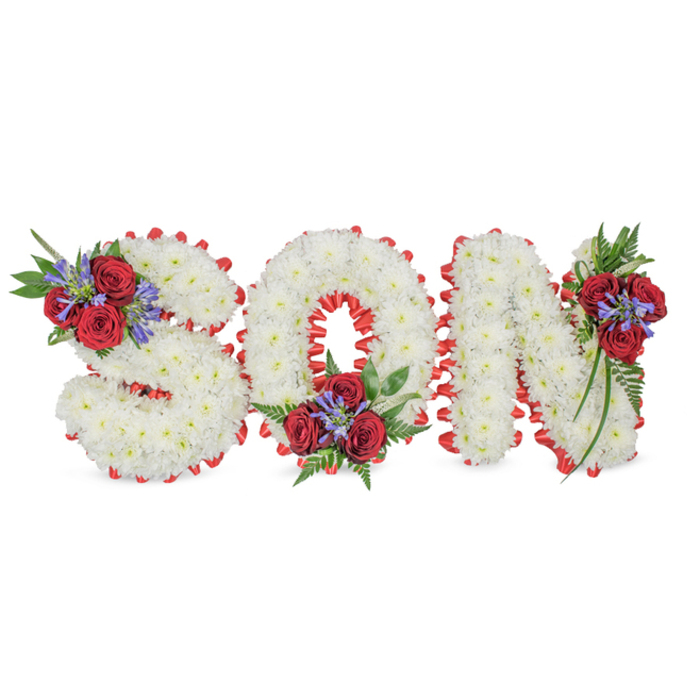 A poignant, handcrafted memorial reads SON in large, three-dimensional letters arranged horizontally on a stark white surface, the photograph highlighting the neat workmanship and emotional restraint of the design. Each character is constructed from a dense blanket of small white spray chrysanthemums so closely set that the letters appear soft and pillowy, evoking peace and purity. The outer edge of every letter is framed with a bright red satin ribbon, skillfully folded into a scalloped trim that crisply defines the shapes and gives the composition a traditional, respectful silhouette. Decorative clusters are thoughtfully placed to add colour and depth: the S carries its floral accent on the upper-left curve, the O on its lower centre, and the N on the upper-right vertical. Within each cluster are rich red roses, their velvet petals offering a warm, solemn focal point; contrasting blue-purple spikes-likely liatris-introduce a cool, vertical note; and a selection of deep green foliage and fern-like fronds softens the overall geometry and introduces gentle movement. The arrangement suggests a soft, comforting scent of roses layered over fresh greenery, and reads as an intimate tribute suitable for a funeral service or graveside commemoration. As a piece made by a seasoned florist, its balance of texture, colour and placement is intended to honour the memory of a much-loved son while remaining understated and profoundly respectful-a design commonly requested by families in the Elmers End area for private and chapel services.